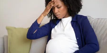 Woman experiencing bleeding during pregnancy on a couch